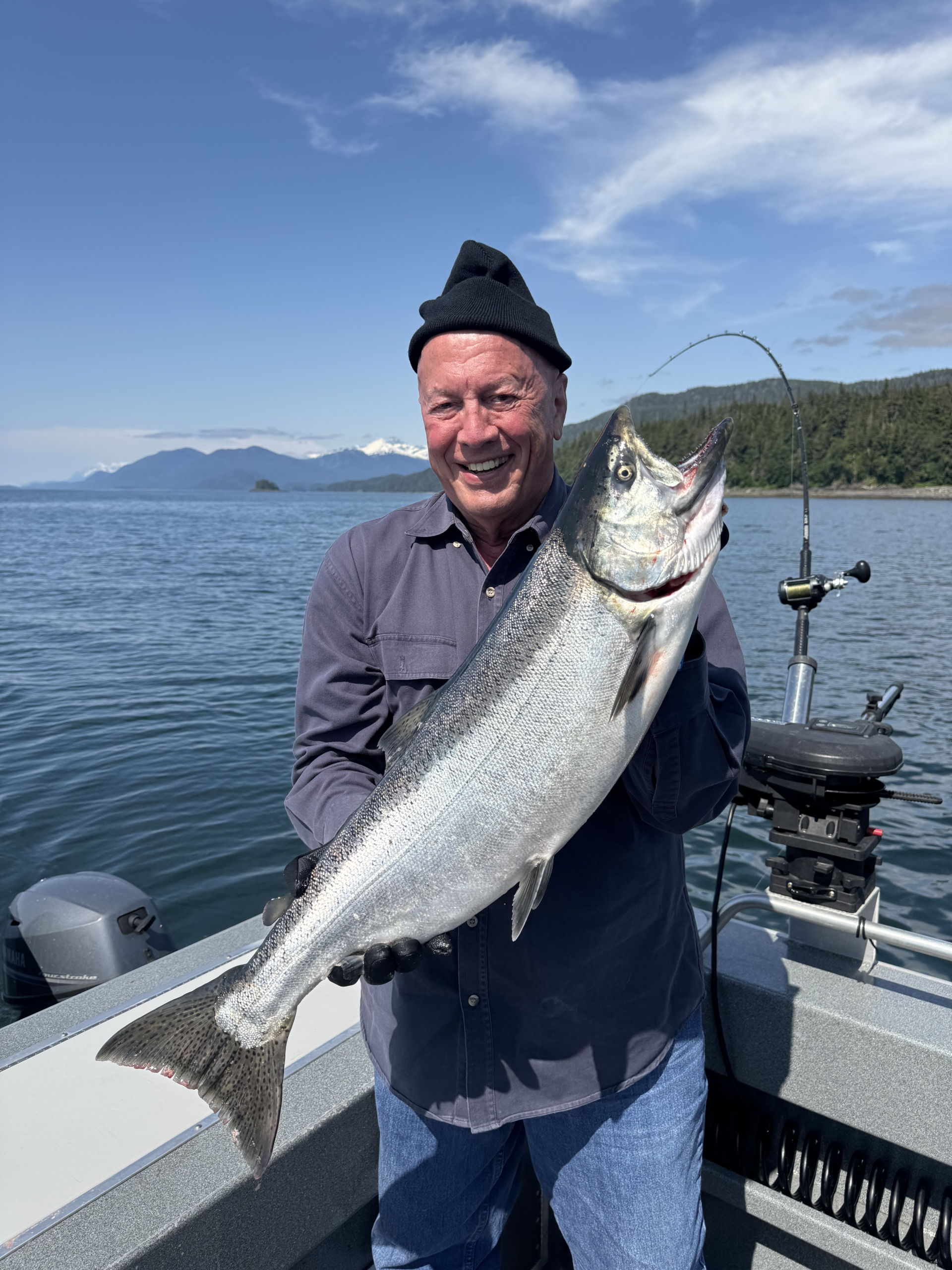 A happy angler holding a large King salmon caught on a private fishing tour in Juneau, Alaska, guided by the crew of Adventures in Alaska.